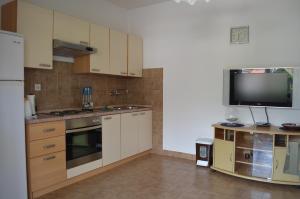 a kitchen with white cabinets and a flat screen tv at Apartments Antonio in Baška