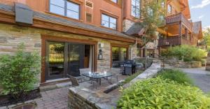 a patio with a table and a grill in front of a building at Étoile du Matin by Rendez-Vous Mont-Tremblant in Mont-Tremblant