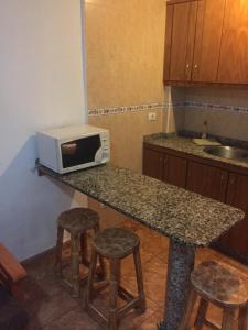 a kitchen with a counter with a microwave and stools at Apartment Yumbo Centrum in Playa del Ingles