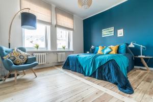 a blue bedroom with a bed and a chair at Greystone Suites & Apartments in Riga