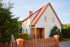 una casa blanca con un techo rojo detrás de una valla en U Roberta en Mrągowo