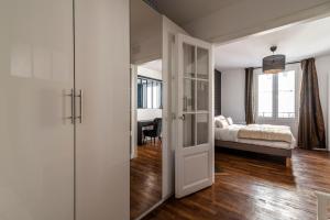 Schlafzimmer mit einem Bett und einer Tür, die in ein Zimmer führt in der Unterkunft MM Suites Cathédrale in Reims