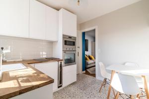 a kitchen with white cabinets and a table and chairs at MM Suites Cathédrale in Reims