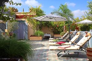 a row of lounge chairs with umbrellas on a patio at Riad Noos Noos in Marrakesh