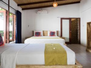 two beds in a room with two windows at Gili Turtle Beach Resort in Gili Trawangan