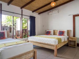 two beds in a room with windows at Gili Turtle Beach Resort in Gili Trawangan