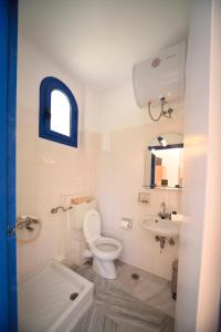 a white bathroom with a toilet and a sink at Hotel Palazzo in Archangelos