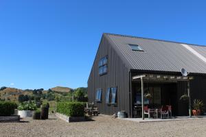 a black barn with tables and chairs outside of it at The Loft at Te Kumi Tirohanga in Te Kuiti