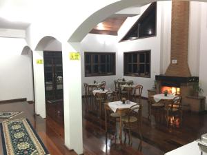 a dining room with tables and chairs and a fireplace at Pousada Casa Da Colina in Santo Antônio do Pinhal