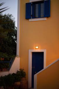 a blue door with a window and a blue shutter at Hotel Palazzo in Archangelos