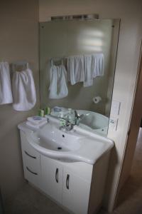 ein Badezimmer mit einem weißen Waschbecken und einem Spiegel in der Unterkunft Vaiakura Holiday Homes in Rarotonga