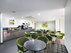 a restaurant with tables and green chairs and a counter at Value Suites Green Square in Sydney
