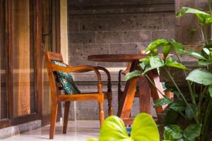 una sedia in legno seduta accanto a un tavolo con una pianta di Bali Asli Lodge by EPS ad Ubud
