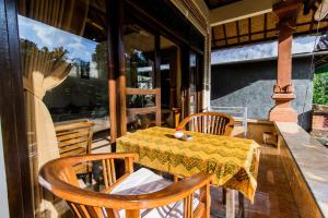 a table and chairs on a screened porch with a table and a table at Bali Asli Lodge by EPS in Ubud