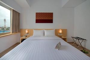 a large white bed in a room with a window at Whiz Hotel Sudirman Pekanbaru in Pekanbaru