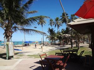 a beach with tables and palm trees and the ocean at Apartamento Ametista 2 + Bykes in Maceió