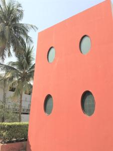 un bâtiment rouge avec des fenêtres circulaires à côté des palmiers dans l'établissement Star Guest House, à Karachi