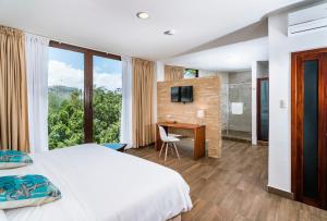 a bedroom with a bed and a desk with a television at Hotel La Isla in Puerto Ayora