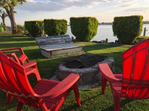 two red chairs and a fire pit next to the water at Lakeshore Inn Water Front in Moses Lake