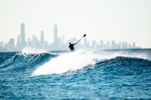 un hombre montando una ola en una tabla de surf en el océano en The Lotus, en Gold Coast