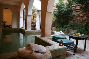 een zwembad met een hond die naast een tafel in een kussen slaapt bij Riad Spa Dar Nimbus in Marrakesh