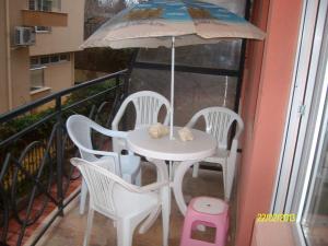 a table and chairs on a balcony with an umbrella at NELLY Guest House in Ravda