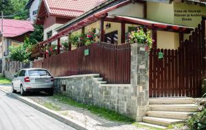 un'auto parcheggiata di fronte a una casa con una recinzione di Casa de Vacanta Razvan si Andrei a Sinaia