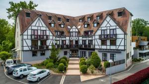 une grande maison avec des voitures garées devant elle dans l'établissement Hôtel Restaurant Les Alizés, à Lipsheim