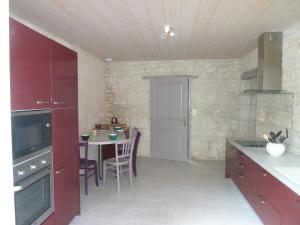 a kitchen with red cabinets and a table with chairs at LES 3 PETITS COCHONS in Le Bouchet
