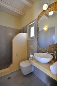 a bathroom with a sink and a toilet and a mirror at Portes Houses in Koufonisia