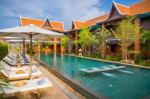 暹粒的住宿－Khmer House Resort，一个带躺椅和遮阳伞的度假村游泳池