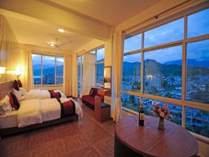 ein Hotelzimmer mit einem Bett und einem großen Fenster in der Unterkunft Hotel City Inn - Mountain View in Pokhara