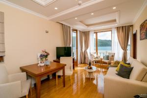 赫尔采格诺维Hedera Residences - Kumbor的客厅里有一张桌子、一张沙发和一台电视