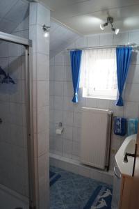 een badkamer met een douche, blauwe gordijnen en een raam bij Ferienwohnung Coordes in Dornumersiel