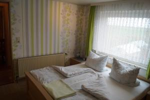 a bedroom with a bed with pillows and a window at Ferienwohnung Coordes in Dornumersiel