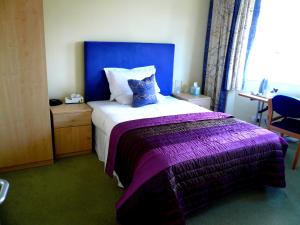 a bedroom with a large bed with a purple blanket at Malvern House in High Wycombe
