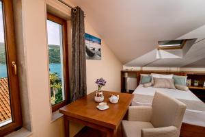 ein Schlafzimmer mit einem Bett, einem Tisch, einem Bett und einem Fenster in der Unterkunft Hedera Residences - Kumbor in Herceg-Novi