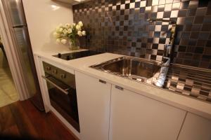 a kitchen with a stainless steel sink and black tiles at Ballarat Premier Apartments in Ballarat +62 photos