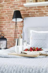a tray of strawberries on a bed with a tea kettle at Hapsal Dietrich apartemendid in Haapsalu