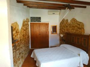 a bedroom with a bed and a stone wall at Casa rural el turmell in Xert
