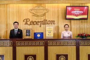Dos personas están detrás de una recepción. en Huong Giang Hotel Resort & Spa, en Hue