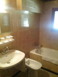 a bathroom with a sink and a toilet and a tub at Hotel Restaurant Les Rosieres in Manigod
