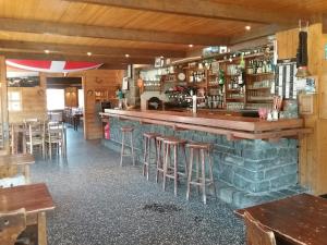 a restaurant with a bar with stools and tables at Hotel Restaurant Les Rosieres in Manigod
