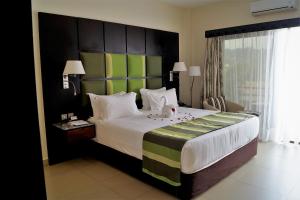 a bedroom with a large bed with a large headboard at Best Western Premier Garden Hotel Entebbe in Entebbe