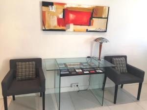 a glass desk with two chairs and a lamp at Au Cœur des Remparts in Aigues-Mortes