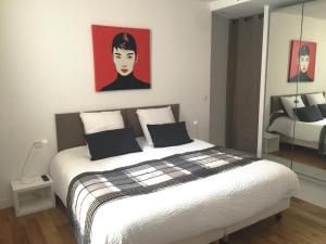 1 dormitorio con 1 cama con una pintura en la pared en Au Cœur des Remparts, en Aigues-Mortes