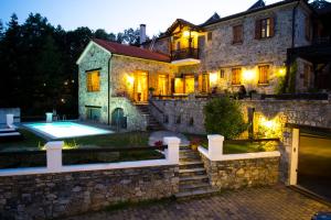 a large stone house with a swimming pool in front of it at Eos - Authentic Experience in Skíti