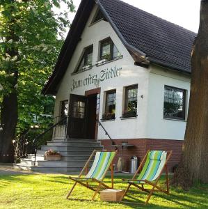dos sillas de jardín sentadas frente a una casa en Landhotel "Zum ersten Siedler", en Brieselang