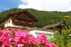 Um edifício com flores cor-de-rosa à frente. em Pension Gatterer em Maria Luggau