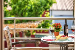 a table with two glasses of wine and a bowl of fruit at ILIDA apartments in Nea Peramos